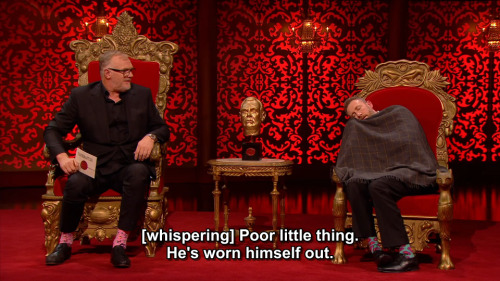 [ID: Two screencaps from Taskmaster. Alex Horne is slumped over in his chair, feigning sleep while d