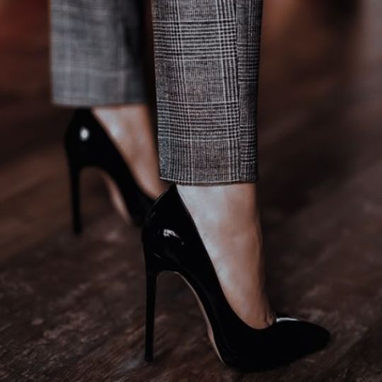 An image of a person in grey pants with black heels from the knee down