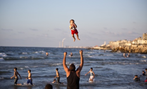 A Palestinian man plays with his baby on a beach on September 7, 2014 in Gaza City. (Mahmud Hams/AFP