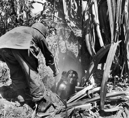 historicaltimes:A U.S soldier offers his hand to a woman leaving a cave where she had hidden with he