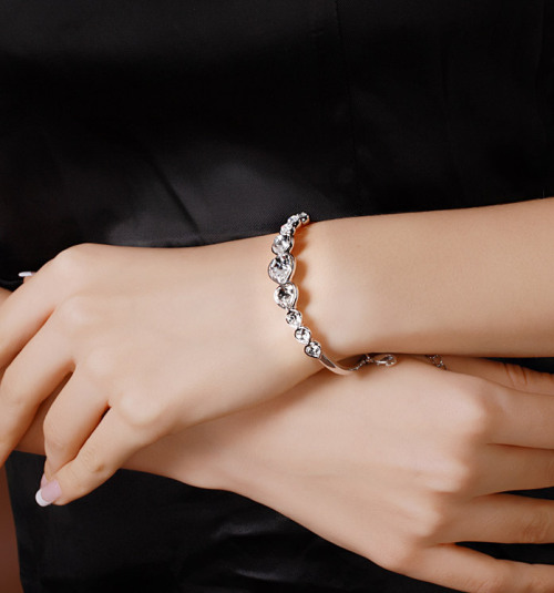 Feminine and romantic, this exquisite rhodium-plated bangle features large, heart-shaped clear cryst