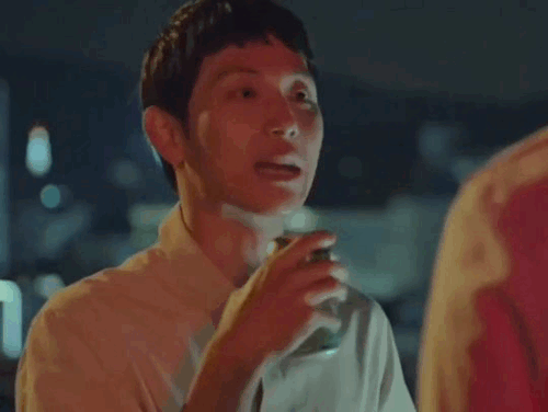 Jongwoo pointing to himself with the hand holding the can, before shaking his head.