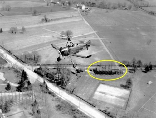 A Pitcairn PAA-1 Sport autogiro with one passenger flies over the Bryn Athyn glass factory (circled)