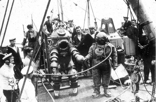 Two divers, one wearing the “Tritonia” ADS and the other standard diving dress, preparin