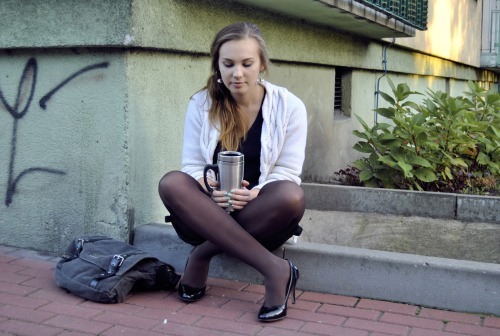 Lovely blonde in black opaque pantyhose and high heels drinking coffee in the street. Woman in panty