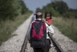 american-radical:  A refugee, hoping to cross into Hungary, carries a child as he walks along a railway track outside the village of Horgos in Serbia, towards the border it shares with Hungary August 31, 2015. (REUTERS/Marko Djurica) Hungary has recently