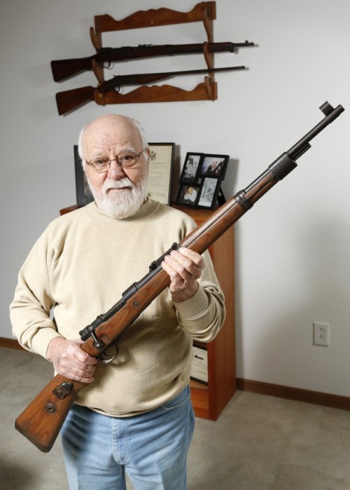 World War II veteran George Banky poses with a German rifle and helmet he acquired during his servic