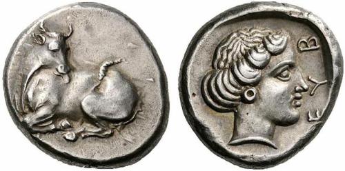 Silver stater of the Euboean League.  On the obverse, a cow licking herself; on the reverse, th
