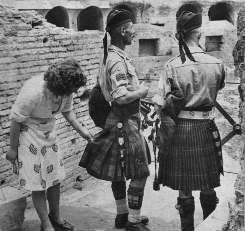 historicaltimes:A curious Italian woman inspects the kilt of a Scottish soldier near the Coliseum af