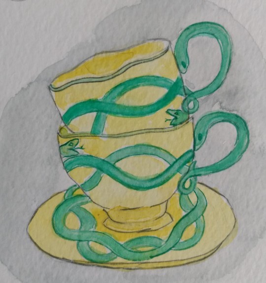 Two teacups are stacked atop each other. They are decorated with curving green snakes. Their handles are also snakes.