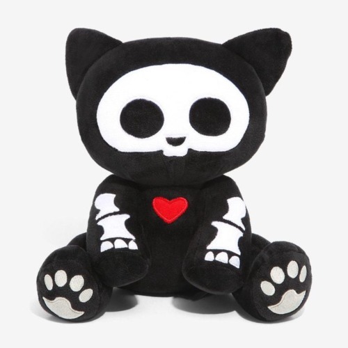 A stuffed animal of a black cat with a white skeleton. The bones are cartoony and simple. There is a small red heart in the middle of its chest.