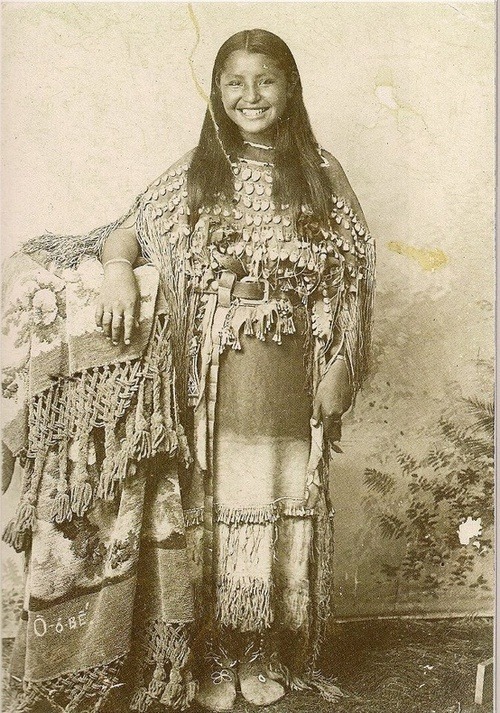 O-o-be (Kiowa) wearing a 3-hide dress decorated with elk teeth. 1895, Fort Sill, Oklahoma