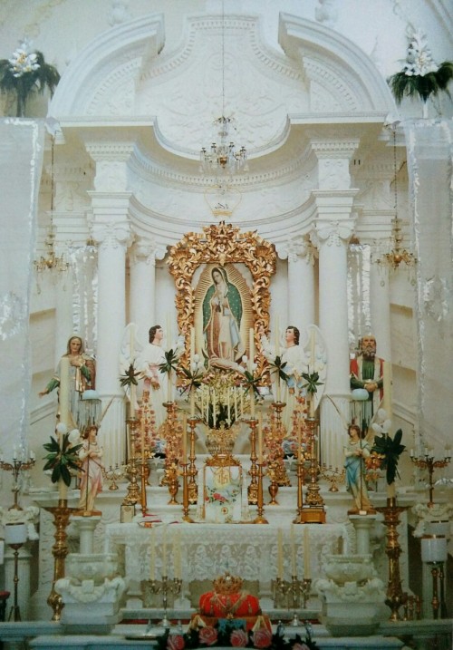 allaboutmary:Main altar with image of Virgin of Guadalupe, plaster angels, and candlesticks, in pari