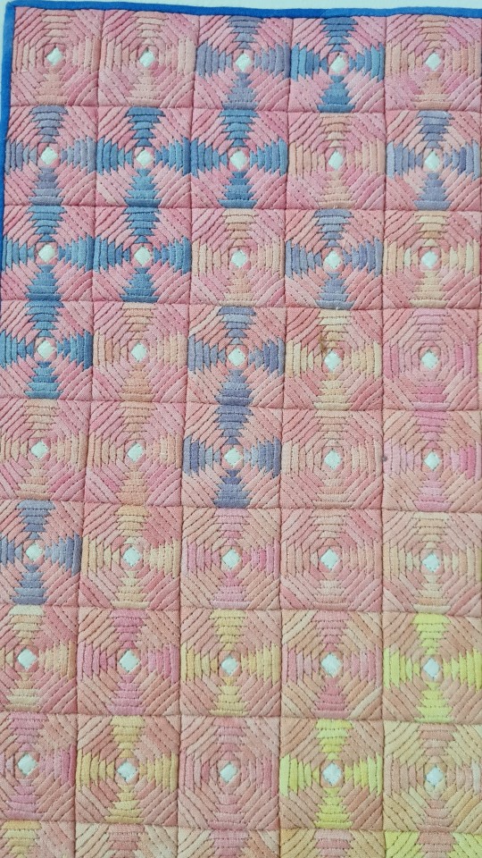 a photograph of a small art quilt in rainbow pastel gradient, hung on a wall. The blocks are a traditional "pineapple block" and are made up of many tiny pieces, with each block measuring approximately 3cm squared. The work is Soft Pride by Amy Pabst.
Close-up showing the gradient.