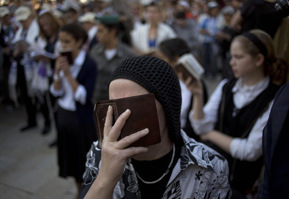 An Orthodox Jewish woman reads from a holy book as she prays at the Western Wall, the holiest site in Jerusalem (Photo by Ariel Schalit/AP via Yahoo News)