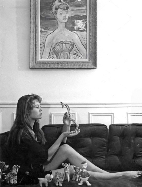 A young Brigitte Bardot at home in Paris with her Disney figurines—and her portrait on the wall. Ear