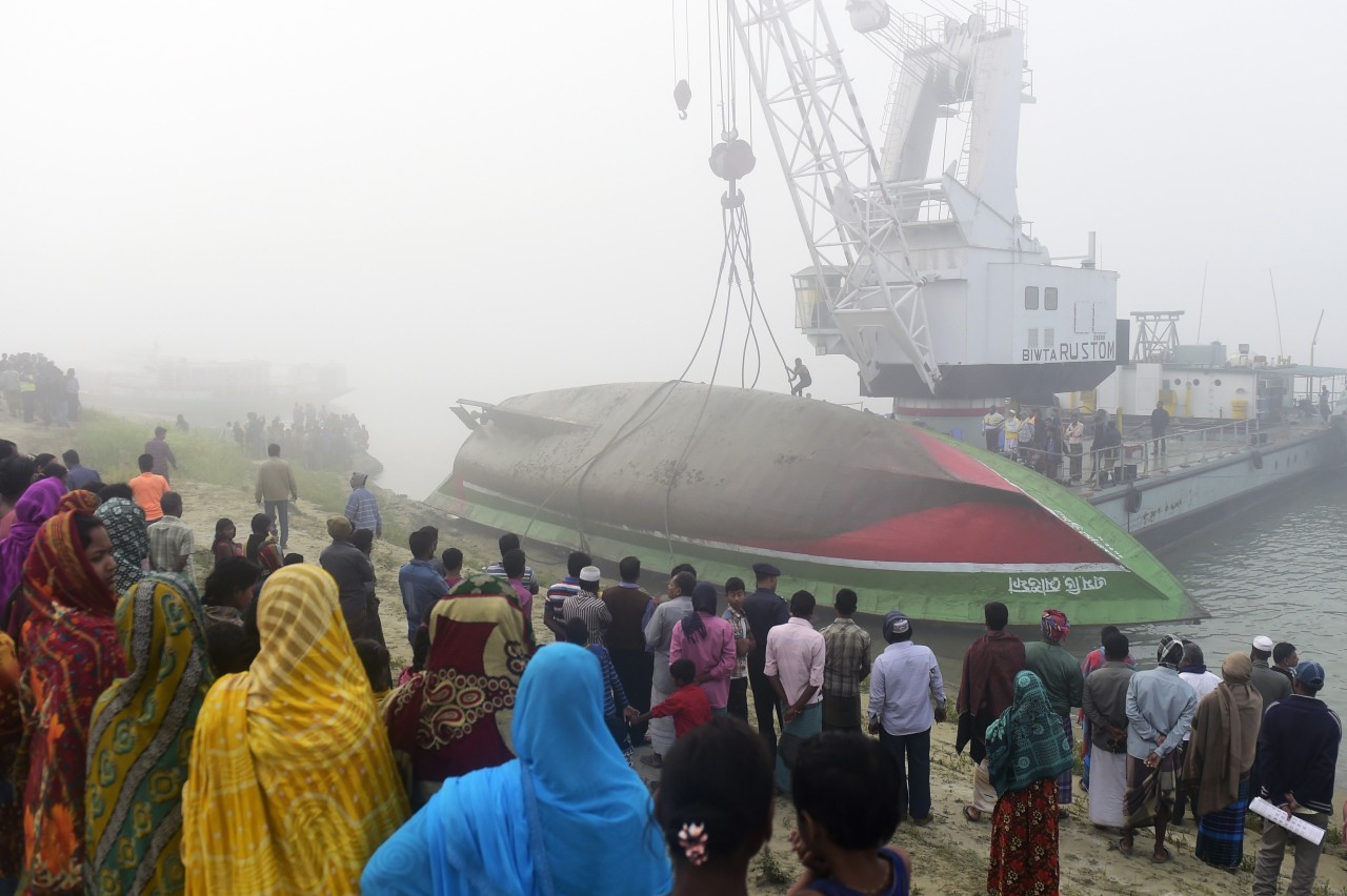 BANGLADESH. Una multitud observa el ferry naufragado en el Río Padma. Las autoridades informaron de 68 el número de muertos por el hundimiento ayer de un ferry con cerca de 200 pasajeros, tras colisionar con un carguero, en un río en el centro de...