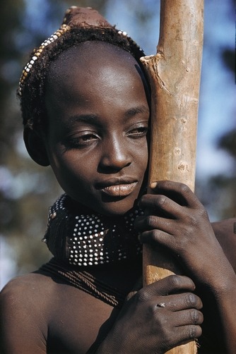 unrar:    A Mwila teen wears her hair in heavy coils adorned with beads, Angola,