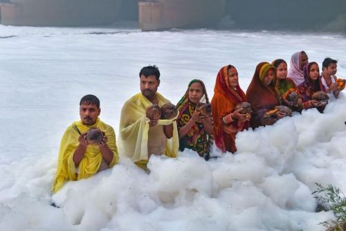 Devotees offer prayers as highly toxic foam floats on the surface of Yamuna river (a sacred river in