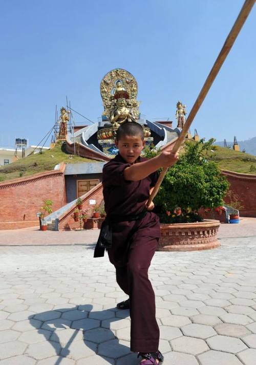  A Kung Fu nun demonstrates a pole form at a Tibetan Temple in Nepal. 