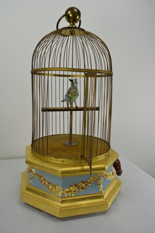 Circa 1870 mechanical singing bird in gilt cage automaton. The bird is in a brass cage with a wood b