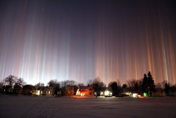 sixpenceee:  Light pillars are shafts of light extending from a bright light source. They’re caused by ice crystals drifting in Earth’s air. They form when the bright light source reflects off the surfaces of millions of falling ice crystals associated