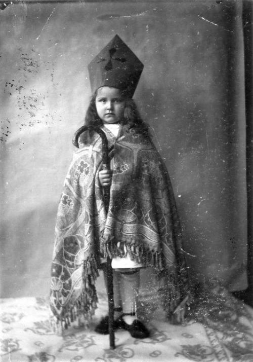A girl dressed up as St. Nicholas with a self-made mitre and a rug as robe. The walking stick serves
