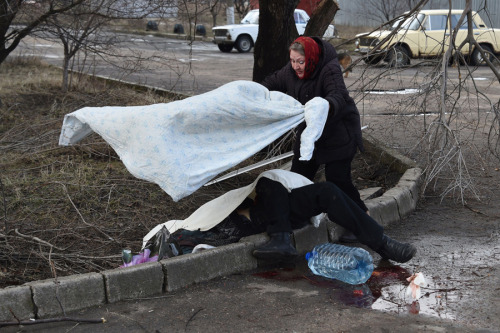 A woman covers the body of a man who was killed during a shelling in a residential area of Donetsk&r