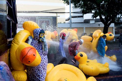 Pro-democracy protesters take cover with inflatable ducks as police use a water cannon during an ant