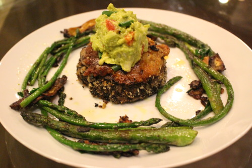 Black bean quinoa burger with melted mozzarella topped with guacamole and surrounded by sautéed aspa