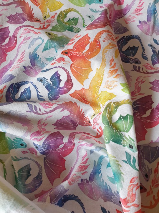 a photo of white fabric printed with dragons in the colour of the rainbow in varying shades