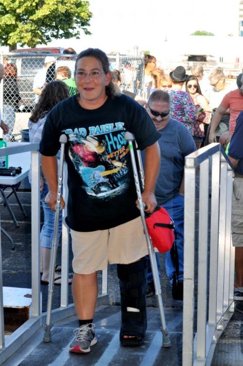 Woman with a black walking boot and crutches boarding a cruise boat.