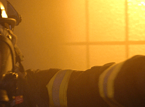 Athena in firefighter gear searching a burning building