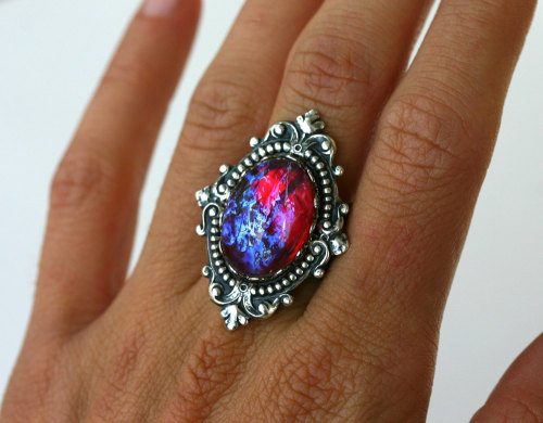 wickedclothes:  Dragon’s Breath Fire Opal Nebula Ring Resting in an ornate, sterling silver setting, this Victorian style ring features a pink fire opal. Resembling the image of a nebula, the pink fire opal shows blue tints when in the light. Sold on