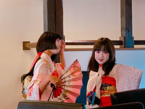 August 2021: Yui-kamuro and Tsukino-kamuro, of Suehiro okiya, mimicing dance movements off-stage whi