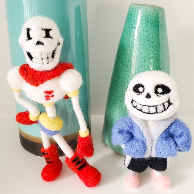 A photo of needle felted Papyrus and Sans from Undertale. They are standing in front of two blue-green vases. Papyrus has his wrist on his hip and Sans has his hands in his pocket.