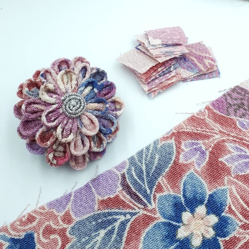Three stages of making a kanzashi piece: the raw fabric, the cut squares, and the final piece. Somet