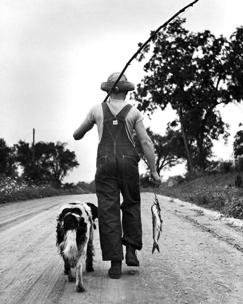 From the September 3, 1945 SPEAKING OF PICTURES photo essay - “…These Record the Pleasures of a Boy and his Dog.” Pictured here are Larry Jim Holm and his dog Dunk heading home after a long summer day of fishing in Oskaloosa, Iowa.“ (Myron Davis—The...