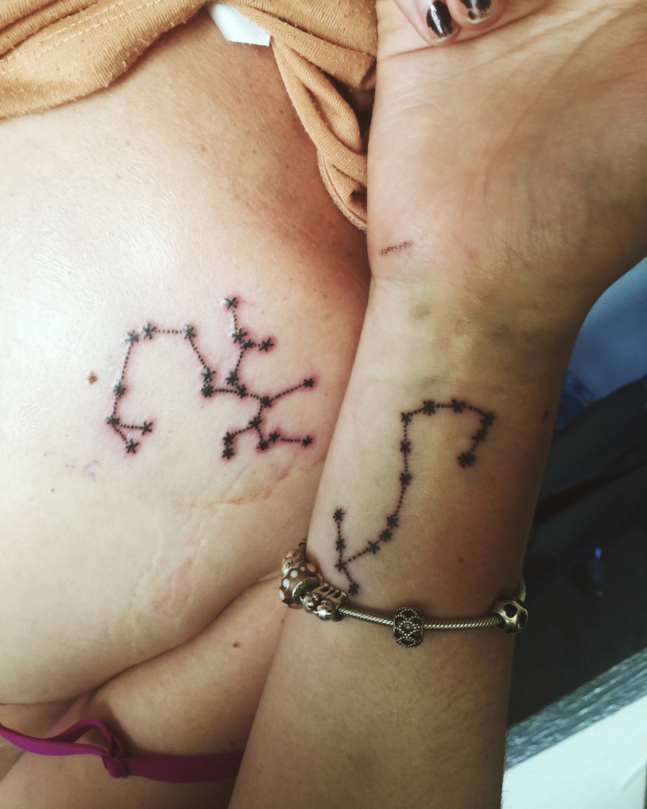 Cancer and Aquarius constellation tattoos on the arm.