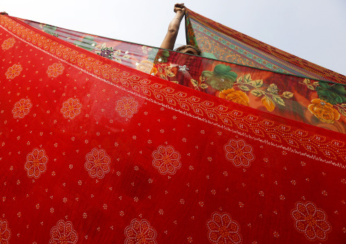 fotojournalismus: A female Hindu pilgrim dries saris after taking a dip in the waters of Ganges rive