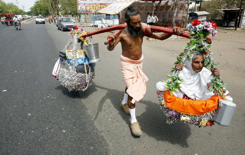An Indian devotee carries his 88-year-old old visually impaired mother on his shoulders in Bhopal, A