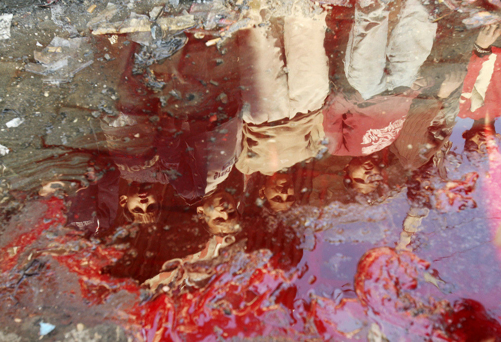 ali-badi:  Palestinian children, check the pool of blood after the bombing of an