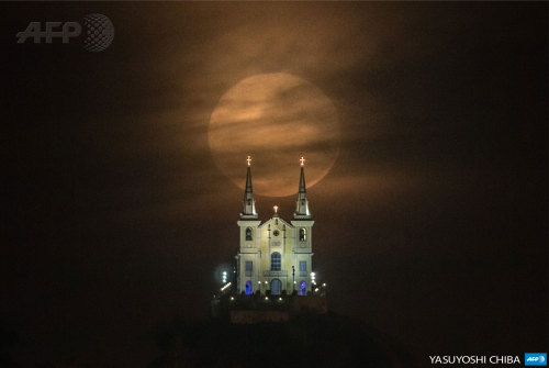 afp-photo:BRAZIL, Rio de Janeiro : The full moon descends behind the Nossa Senhora da Penha Church