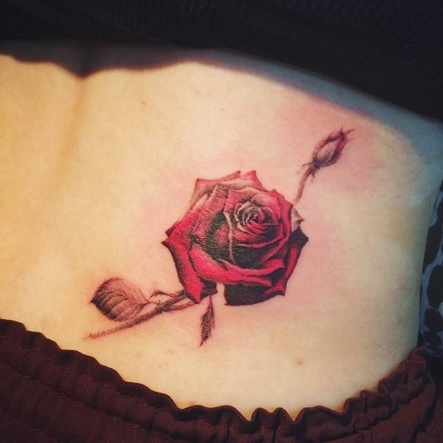 Kiss and rose tattoo on the lower back