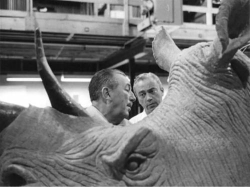 Walt in profile, reviewing the finer points of the rhinoceros figure for Disneyland with animator an