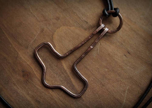 A minimalist hand-hammered Mjolnir necklace, made of copper. The pendant hangs from a 60 cm leather 