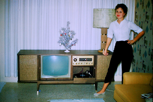 Pretty, smiling woman in Capri pants with TV-Hi-Fi Combo set at Christmas time.  Found photo - early