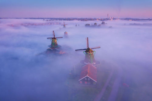 archatlas:     Dutch Windmills in the Fog  Photographer Albert Dros woke up early in the morning to shot the incredible windmills’ village of Zaanse Schans. He creates then a fairy atmosphere looking like a Grimm brother’s novel. The village, usually