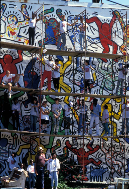 twixnmix:   Keith Haring painting an outdoor mural with city kids in Philadelphia, 1987.  Photos by 