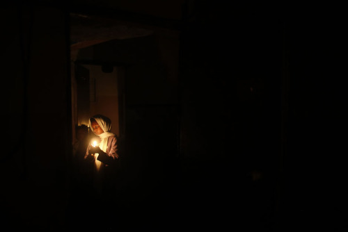 A Palestinian girl lights a candle inside her house during a power cut in Jabalya in the northern Ga